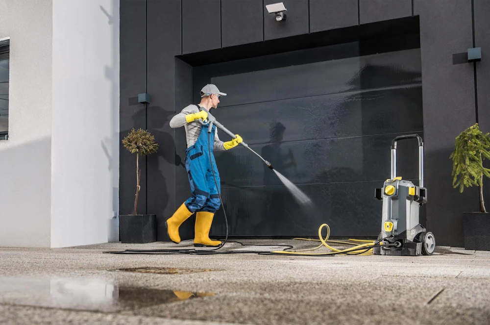 Power washing a black garage door. Top 5 Reasons to Powerwash Your Commercial Facility at the End of Summer